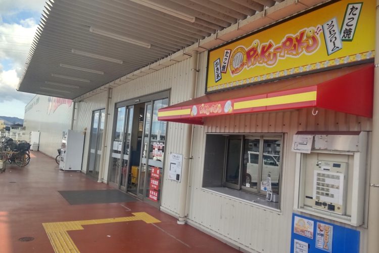 「パクパク」の店頭では、たこ焼きを焼く様子を窓越しに見ることができる。焼き上がるのを待つ間、スーパーで買い物をする客も多い